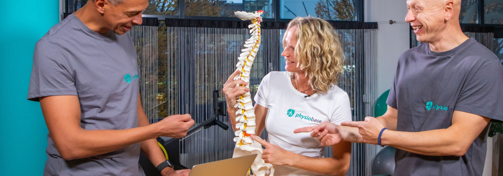 Drei Physiotherapeuten betrachten eine Wirbelsäulenmodell